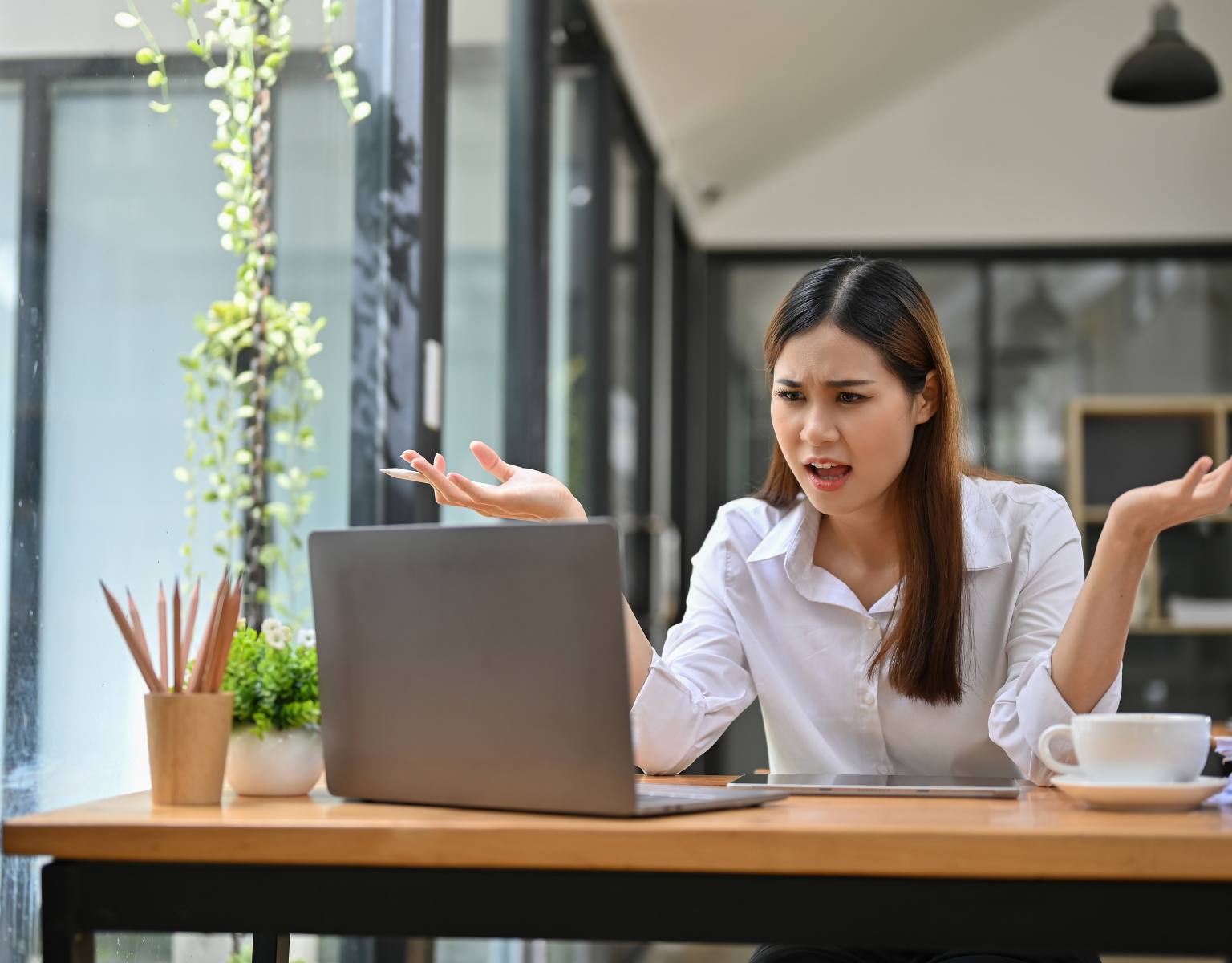 A businesswoman sits at her desk, visibly frustrated as her laptop struggles to connect to the Wi‑Fi.