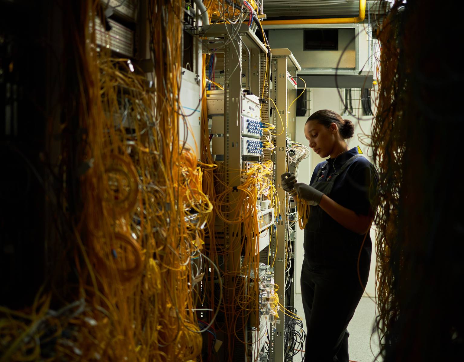 An IT engineer working in a server room with network cables