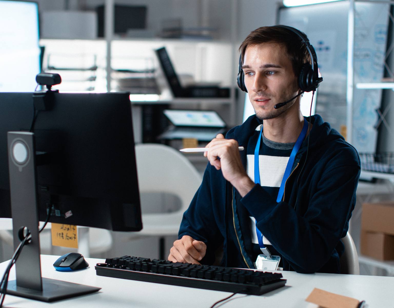 An IT engineer wearing a headset sits at a computer, actively working on a service desk system to provide technical support.